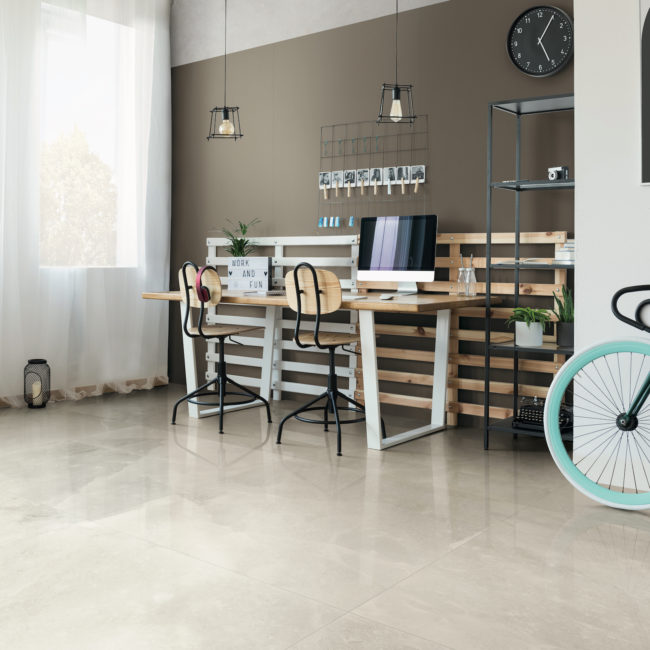 Bike with blue wheel in multifunctional workspace with patterned carpet and clock on white wall